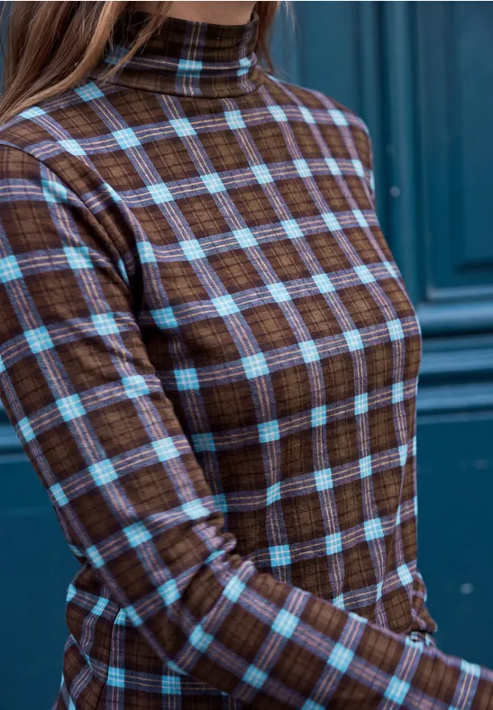 Brauner Rollkragenpullover mit hellblauem Karomuster vor blauem Hintergrund