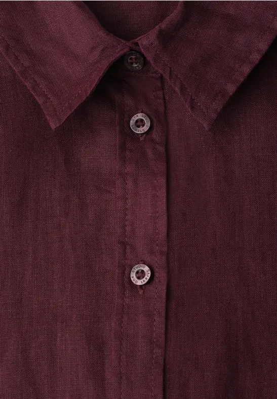 Gros plan d'une chemise bordeaux en lin avec col et patte de boutonnage.