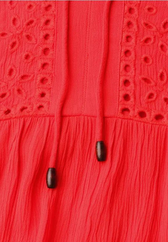 Rode top met broderie anglaise, ruches en koordjes met zwarte kraaltjes.