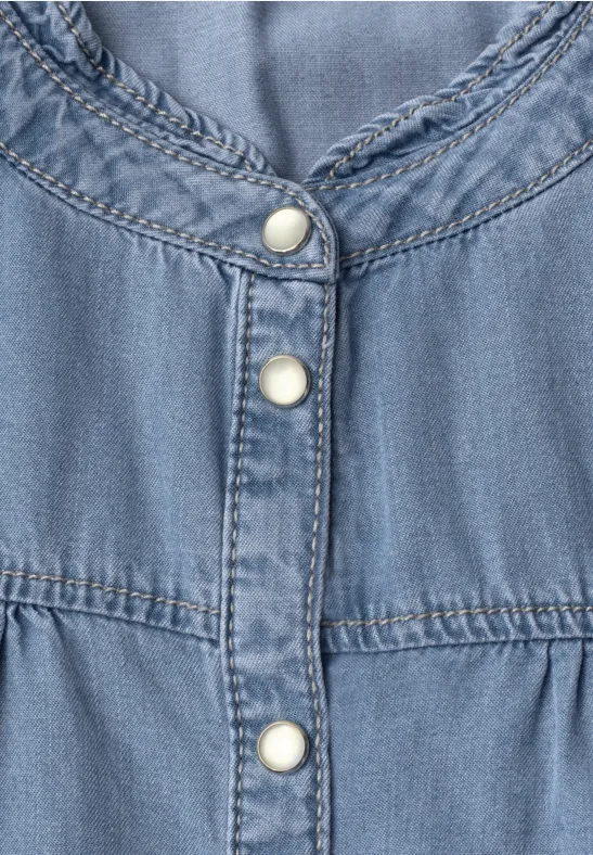 Close-up van een lichtblauwe spijkerjurk met witte drukknoopsluiting