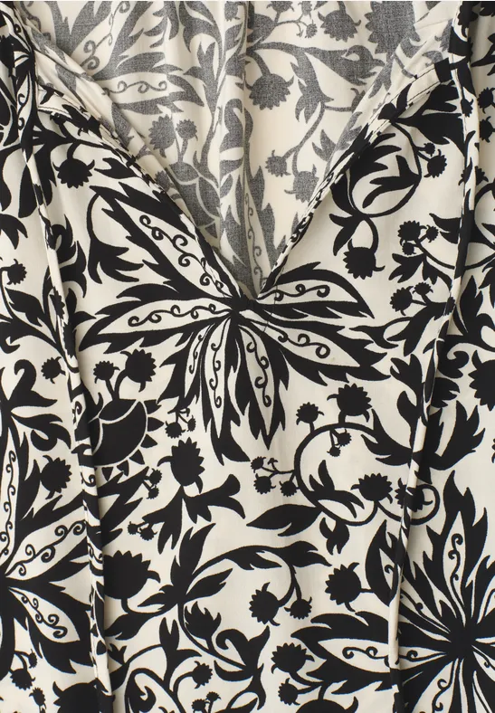 Witte stof met zwart barok bloemen- en bladmotief in V-vorm.