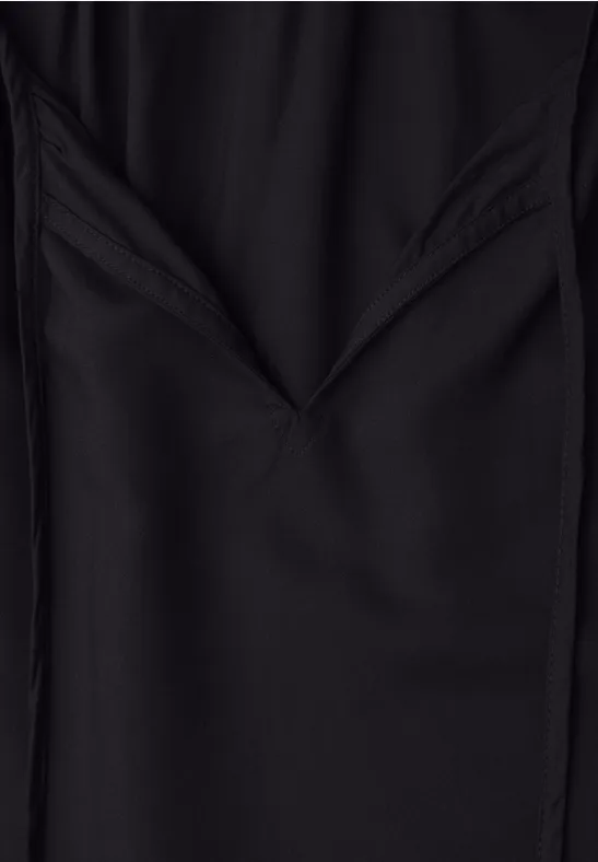 Nahaufnahme eines schwarzen Stoffes mit gefaltetem V-förmigen Muster.
