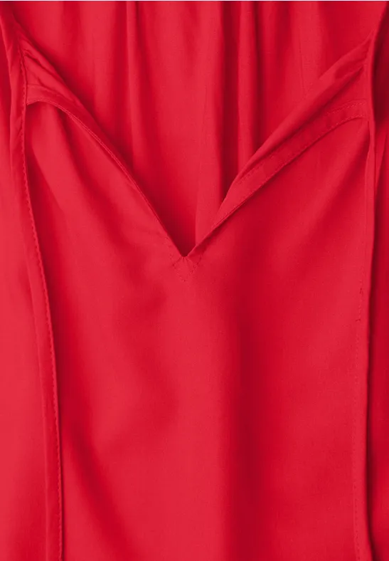 Rotes Kleid mit V-Ausschnitt aus fließendem, einfarbigem Stoff.