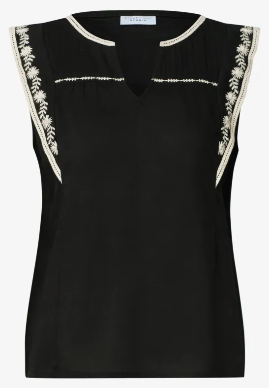Ärmellose schwarze Bluse mit V-Ausschnitt und weißen Stickereien an Schultern und Ausschnitt