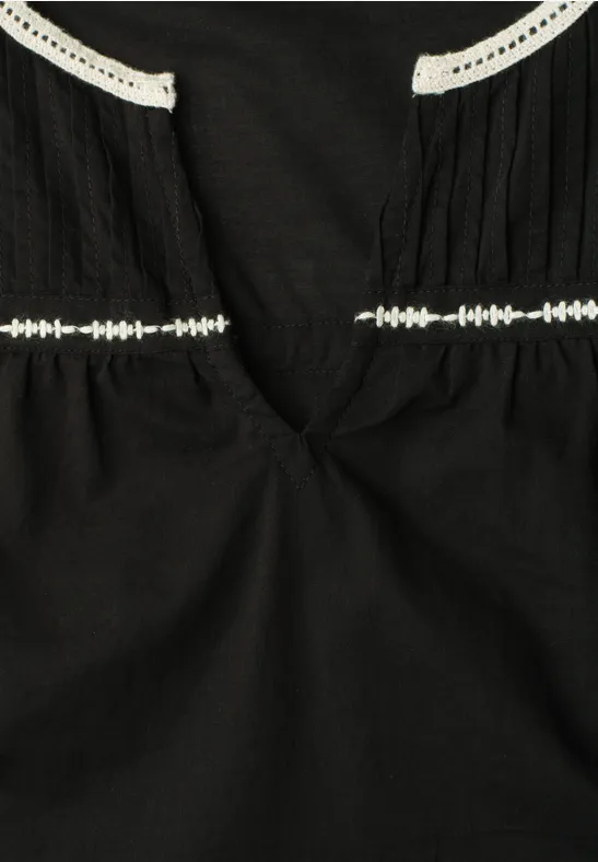 Schwarzes Top mit V-Ausschnitt und weißen Spitzenbändern an Schultern und Taille
