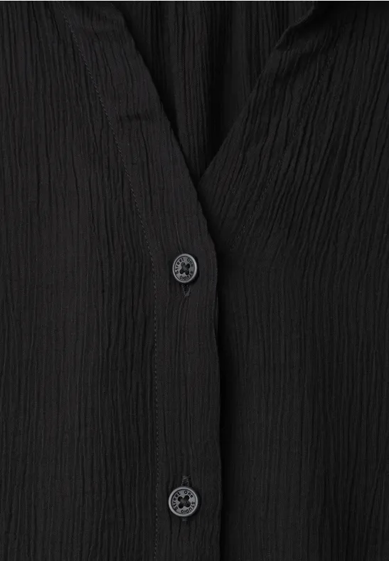 Schwarze Bluse aus geripptem Stoff mit zwei schwarzen Knöpfen.