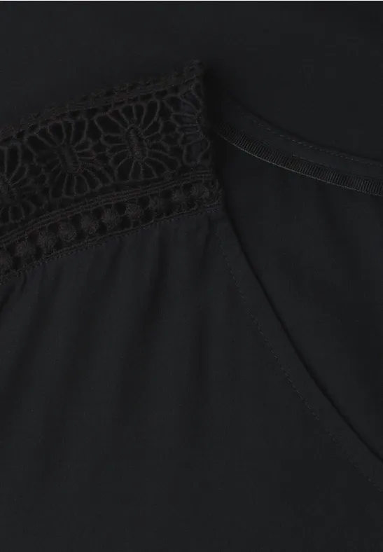 Haut noir avec un élégant détail en dentelle sur l'épaule.