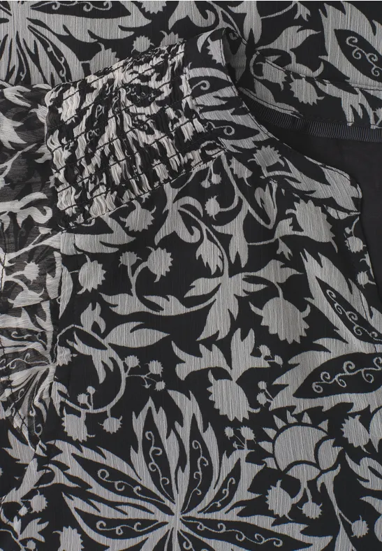 Schwarzes Kleid mit weißen Blumenmustern und gerafftem Oberteil.