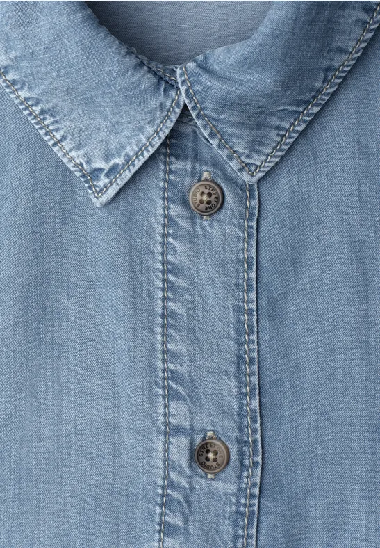 Hellblaues Jeanshemd, Knopfleiste und spitzer Kragen in Nahaufnahme.