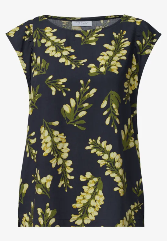 Donkerblauw damestop met losse pasvorm en geelgroen bladpatroon.