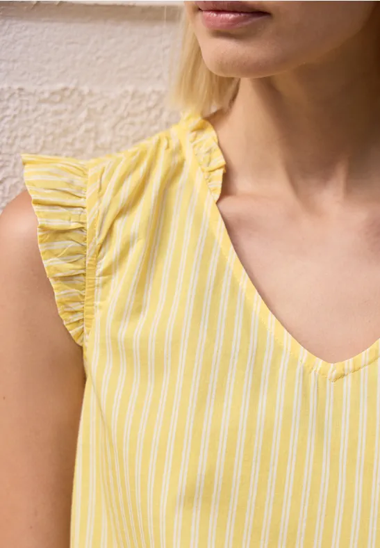 Vrouw in mouwloos geel-wit gestreept topje met V-hals.