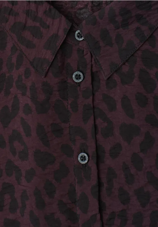 Nahaufnahme eines bordeauxfarbenen Hemds mit schwarzem Leopardenmuster und Knopfleiste.