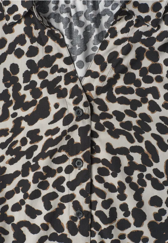 Close-up van een hemd met zwart-bruin luipaardprint op lichte stof en zichtbare knopen.