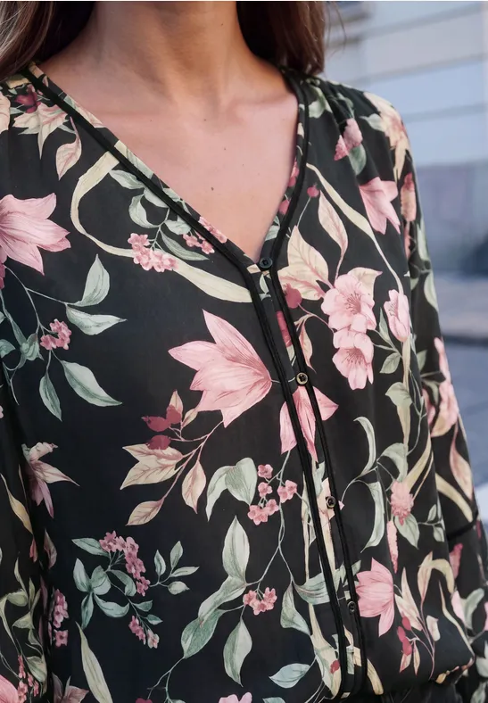 Schwarzes Oberteil mit rosa-weißen Blumenmustern und Knopfleiste im V-Ausschnitt.