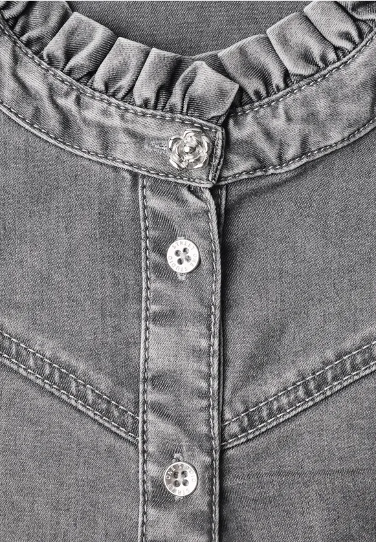 Nahaufnahme eines grauen Jeanshemds mit Rüschenkragen und silbernen Knöpfen.