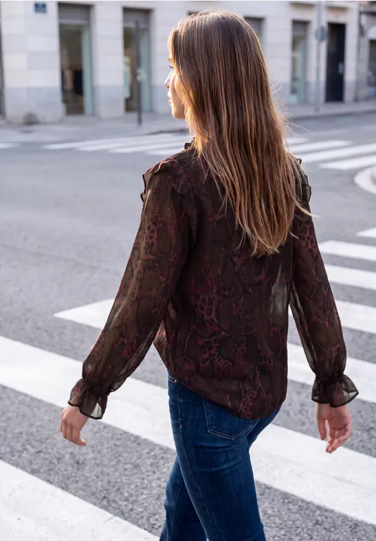 Junge Frau mit braunen Haaren in Bluse und Jeans läuft auf einem Zebrastreifen in der Stadt.