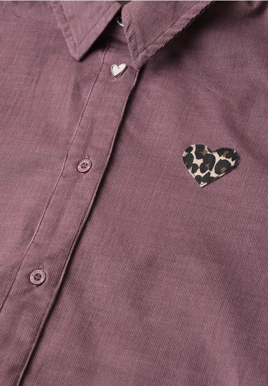 Lila Hemd mit Herz-Button am Kragen und Leo-Herz-Patch auf der Brust.
