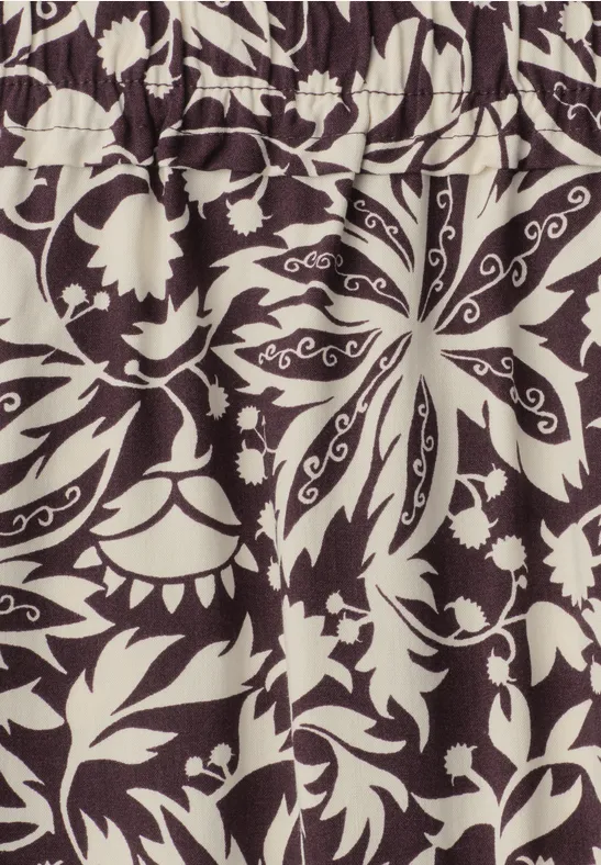 Beige stofpatroon met zwarte, symmetrische bloem- en bladornamenten.