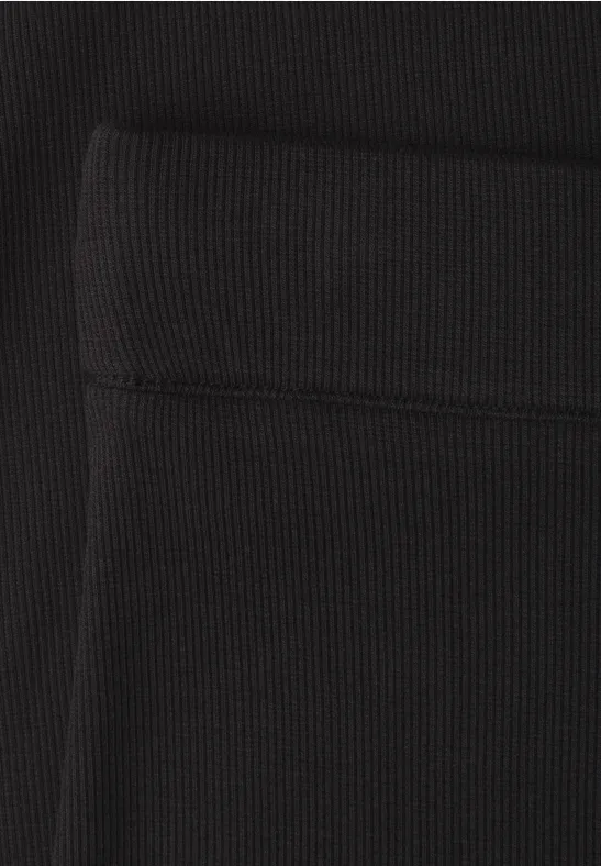 Schwarzer, gerippter Stoff mit sichtbarer Naht und aufgesetzter Tasche.
