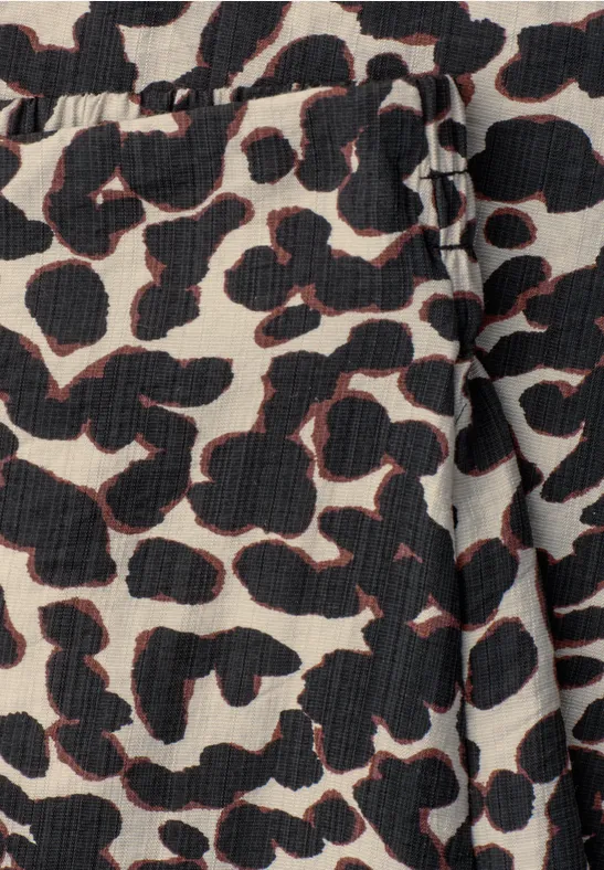 Beige Stoff mit schwarzem Leopardenmuster und dezenten roten Umrandungen.