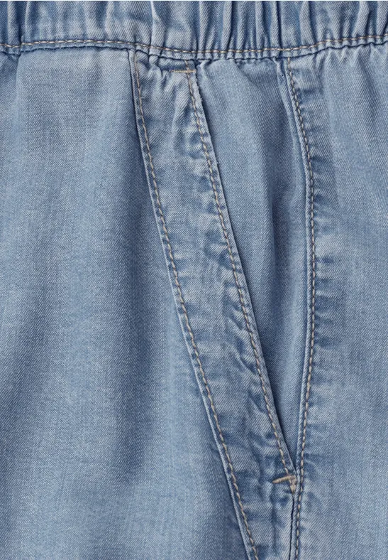 Hellblaue Jeansoptik mit elastischem Bund und schräger Tasche.