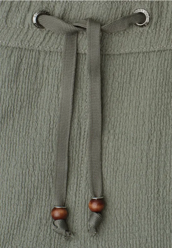 Gros plan d'une ceinture en tissu texturé avec cordon et perles en bois