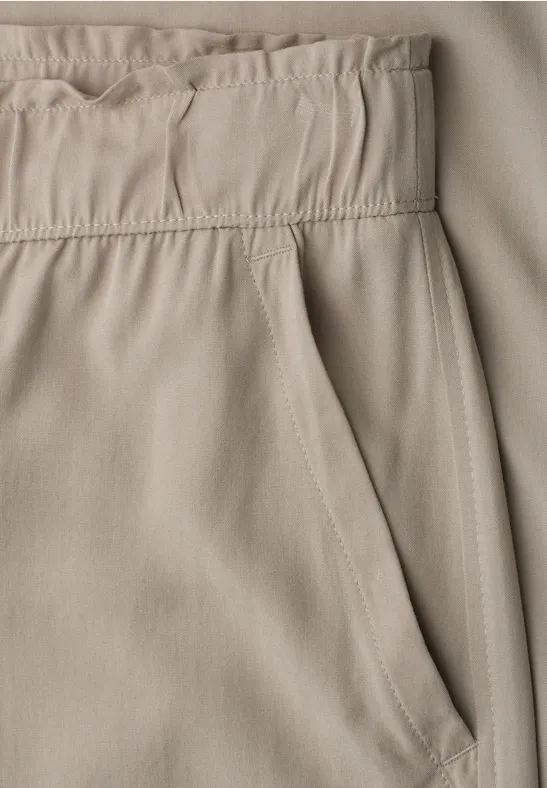 Nahaufnahme einer hellbeigen Hose mit elastischem Bund und seitlicher Eingrifftasche.
