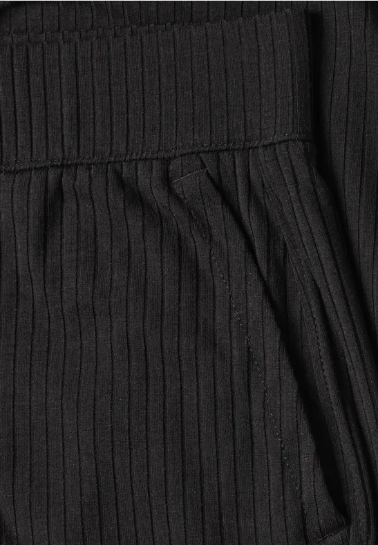Detailansicht eines schwarzen, gerippten Strickstoffs mit seitlicher Tasche.