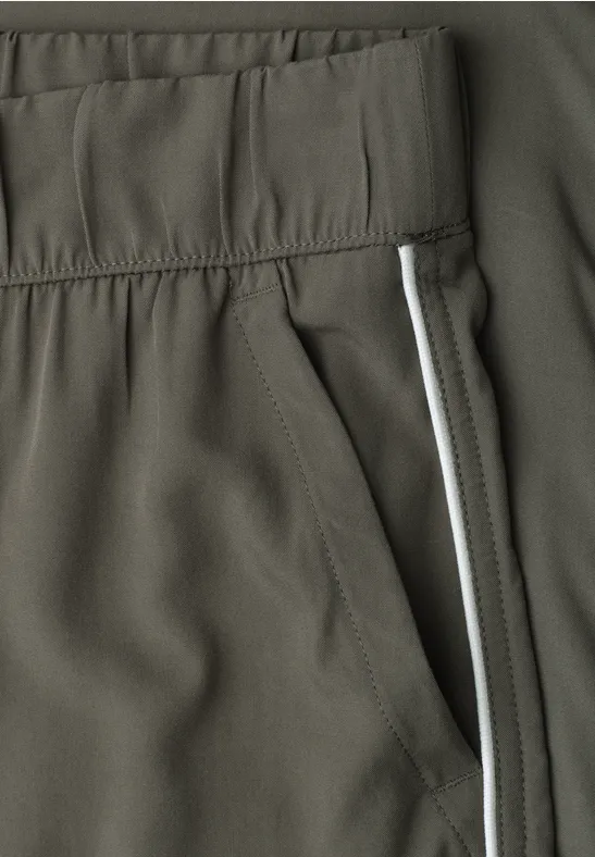 Nahaufnahme einer olivgrünen Sporthose mit elastischem Bund, Seitentasche und weißem Streifen.