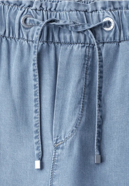 Nahaufnahme eines hellblauen Jeanshosenbunds mit elastischem Tunnelzug und Kordel