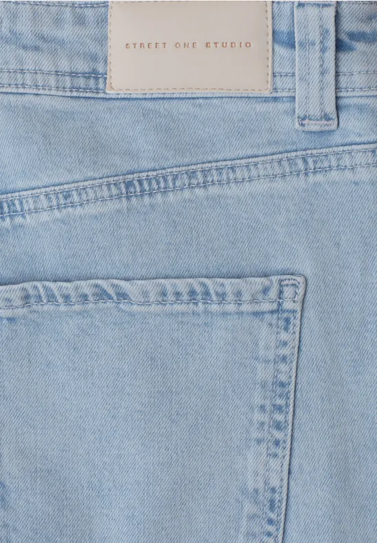 Close-up van lichtblauwe spijkerbroek met achterzak en label in de taille.