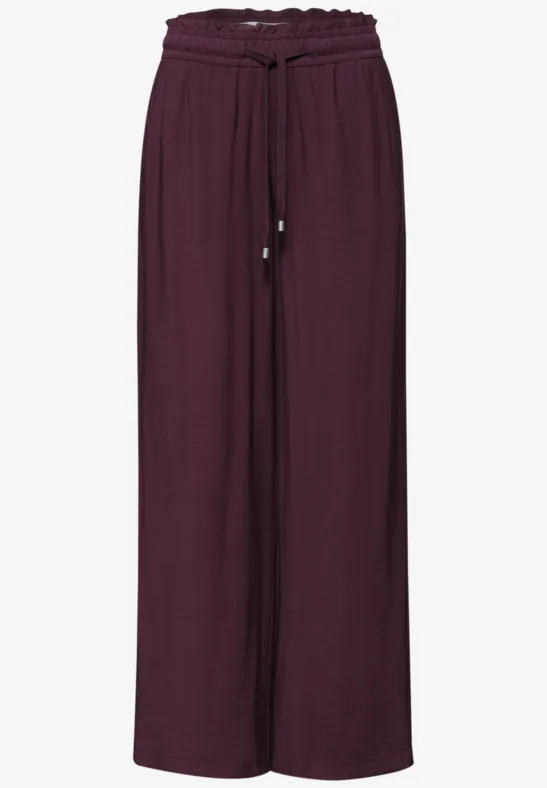 Wijde, vloeiende broek in auberginekleurige stof met trekkoord in de taille.