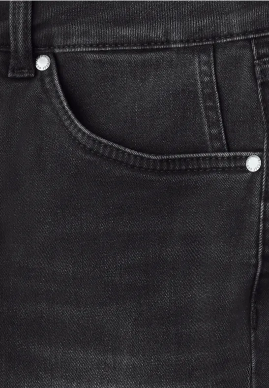 Detailaufnahme einer schwarzen Jeans mit sichtbarer Tasche und silbernen Nieten.