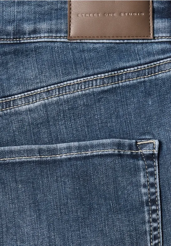 Zbliżenie niebieskich jeansów z skórzaną naszywką i widocznymi szwami.