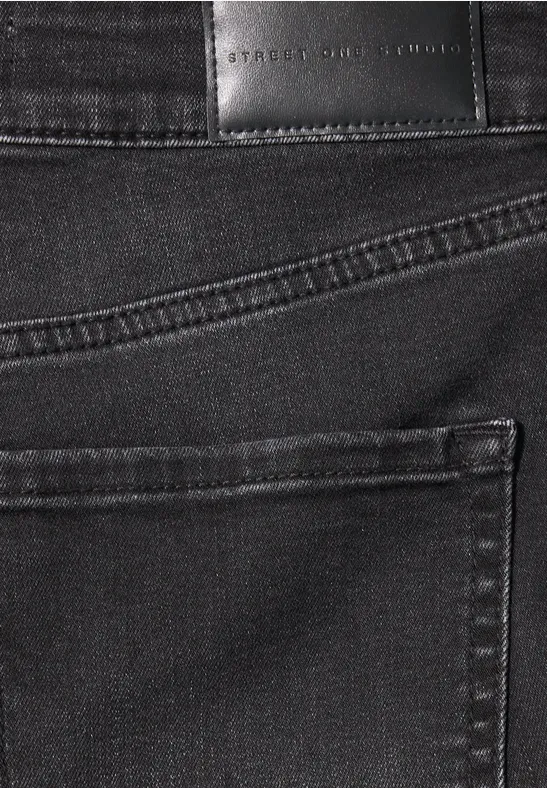 Nahaufnahme einer schwarzen Jeans mit aufgesetzter Gesäßtasche und Markenlederpatch.