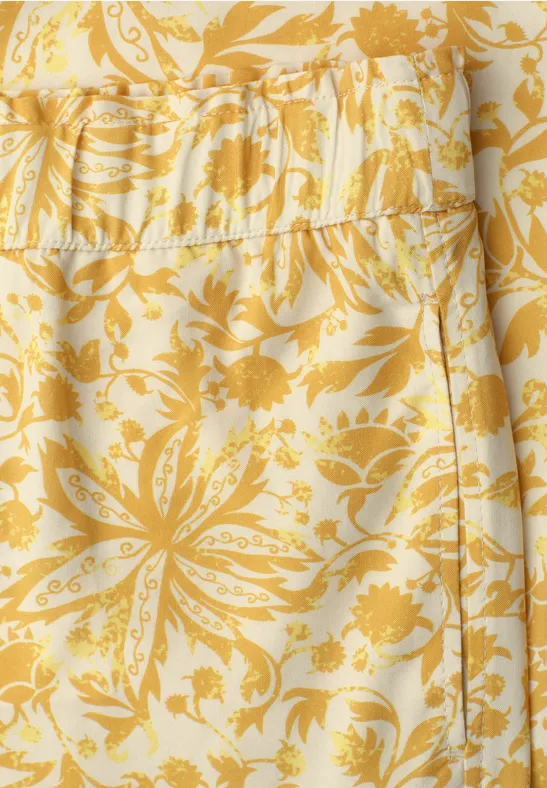 Geel-wit stoffen patroon met bloemenmotief.