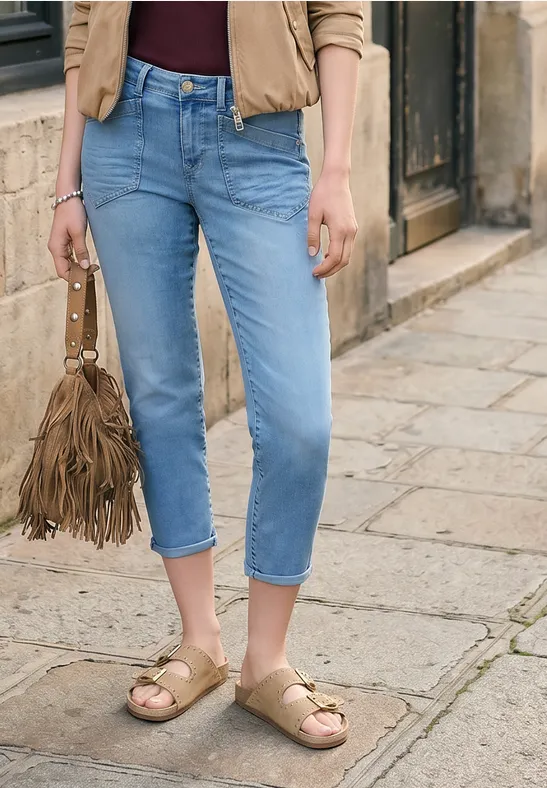 Vrouw in blauw enkellange jeans, beige sandalen en bruine franje-schoudertas op kinderkopjes.