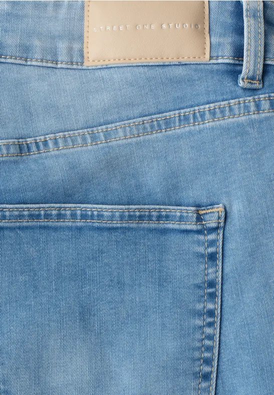 Close-up van een blauwe spijkerbroek met achterzak en ceintuurlussen.