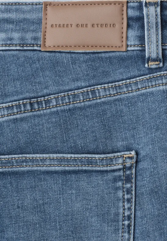 Nahaufnahme einer blauen Jeans mit aufgestickter Lederpatch 'STREET ONE STUDIO' über der Gesäßtasche.
