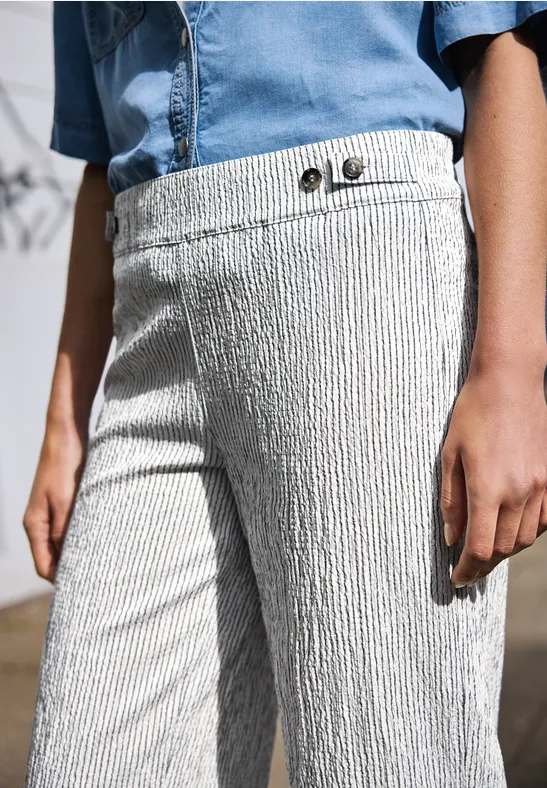 Strukturierte, hellgraue Hose mit Knopfdetail, kombiniert mit blauem Jeanshemd.