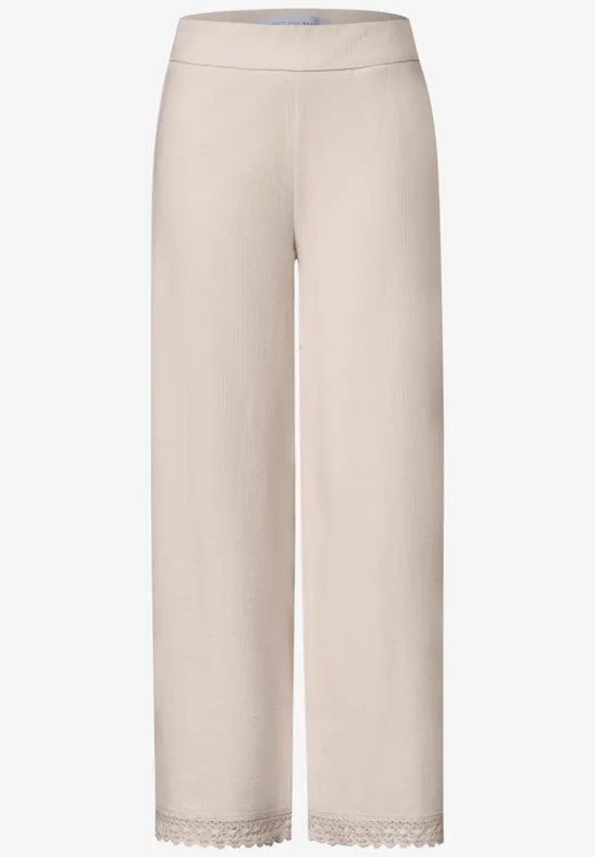 Bequeme, hellbeige Hose mit weitem Schnitt und zarter Spitzenbordüre am Saum