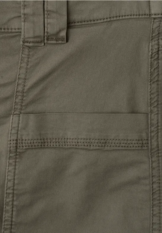 Nahaufnahme einer olivgrünen Stoffhose mit sichtbarer Gürtelschlaufe, Taschenöffnung und dekorativen Nähten.