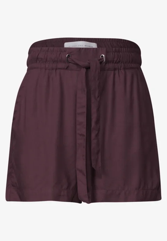 Een korte wijde short in bordeauxrood met elastische tailleband en bijpassende ceintuur
