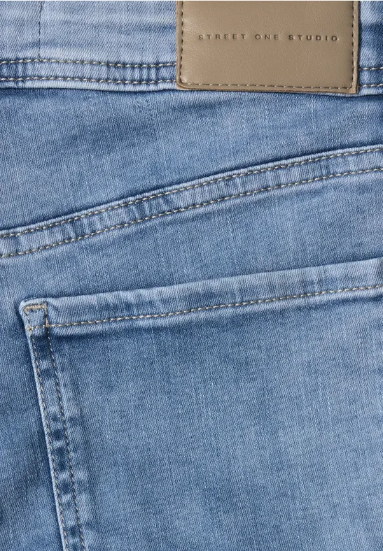 Gros plan sur un jean bleu clair avec poche arrière apparente et étiquette en cuir sur la ceinture.