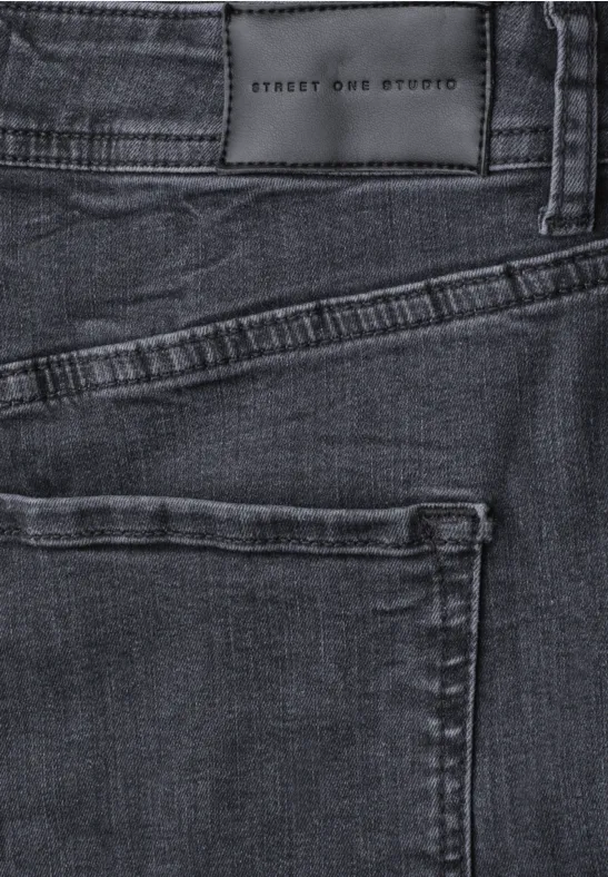 Gros plan sur un jean sombre avec poche arrière et étiquette en cuir STREET ONE STUDIO.