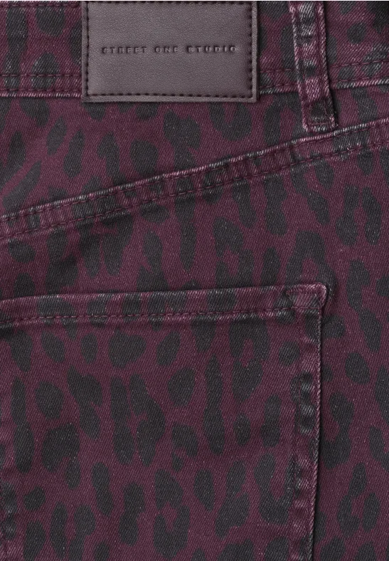 Nahaufnahme eines violett-roten Jeansstoffs mit schwarzen Leopardenflecken und einer Tasche.