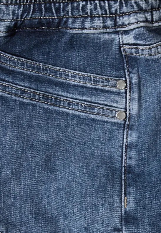 Gros plan sur un jean bleu avec poche et rivets.