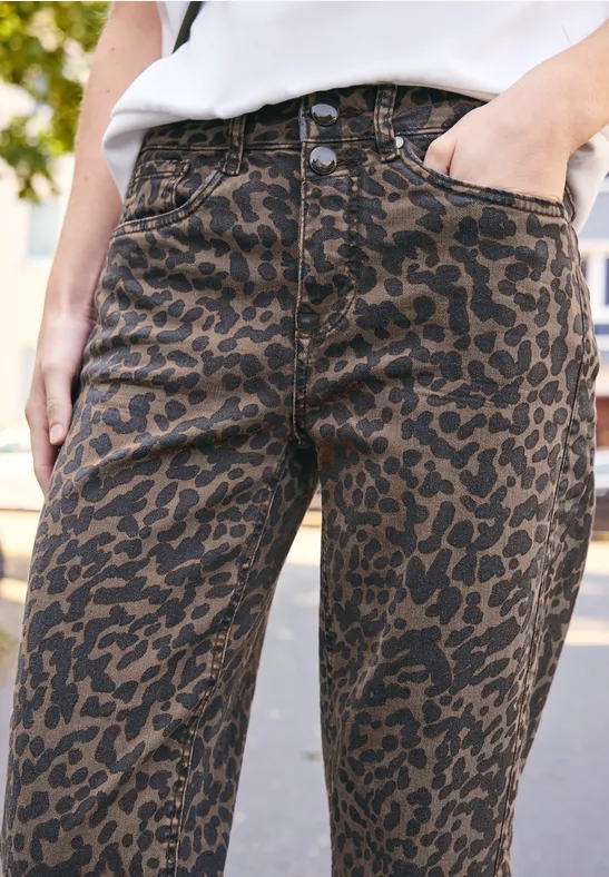 Gros plan d'un jean femme marron à motif léopard, main posée dans la poche.
