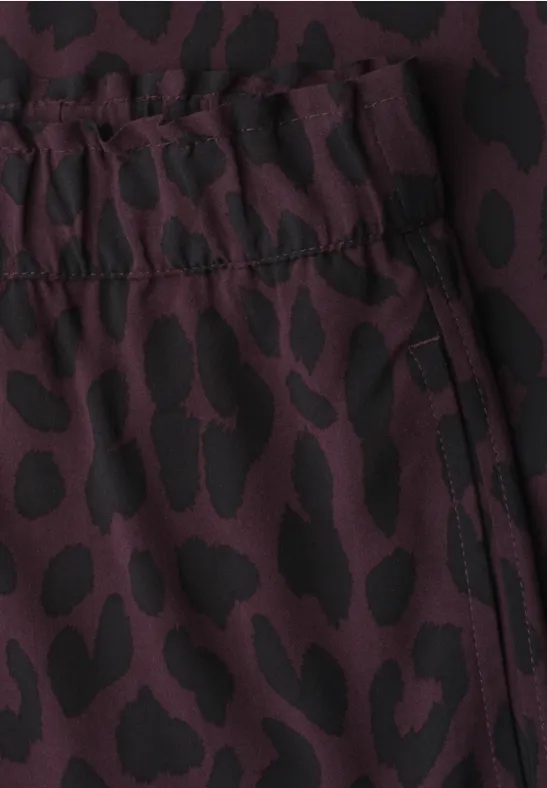 Vêtement bordeaux à taille élastiquée, motif léopard noir et poche zippée.