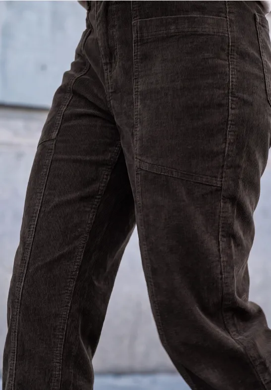 Dunkelbraune Cordhose, Nahaufnahme der Hosenbeine vor einer Betonwand.